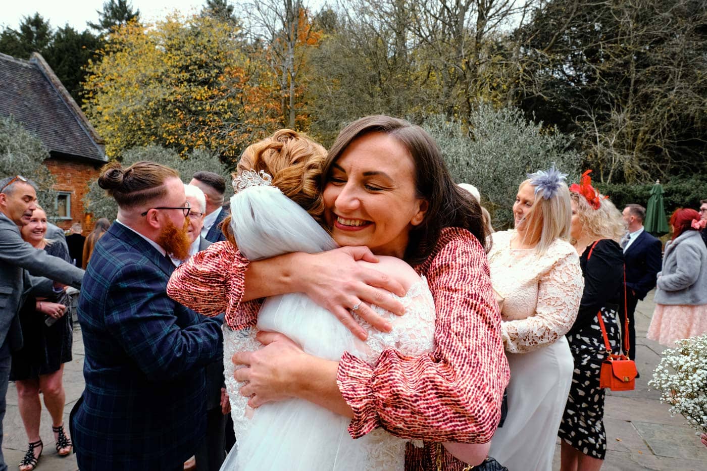 Guest hugging bride by Shustoke Barn wedding photographer Clive Blair
