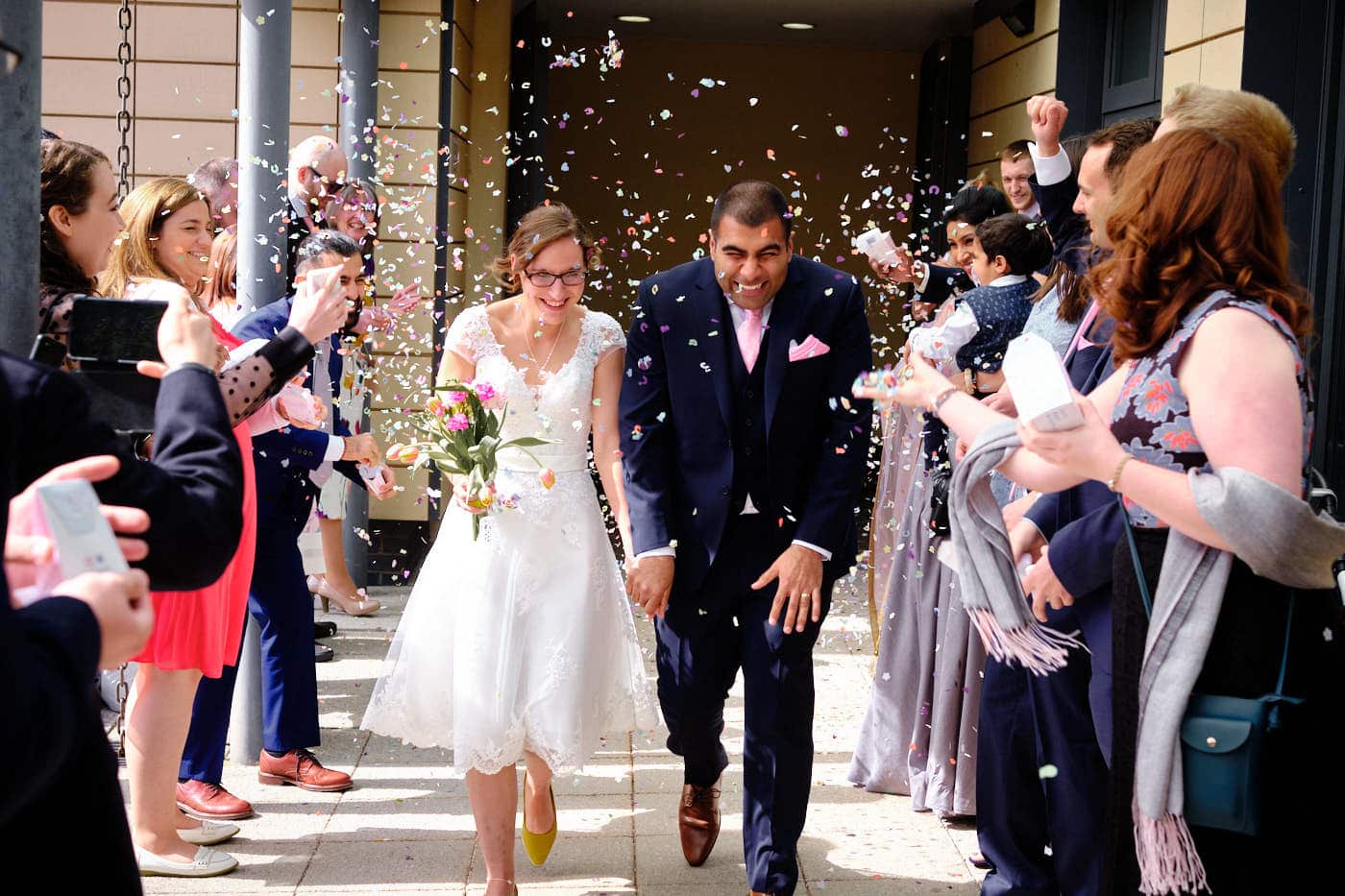 Bride and groom having confetti thrown on their