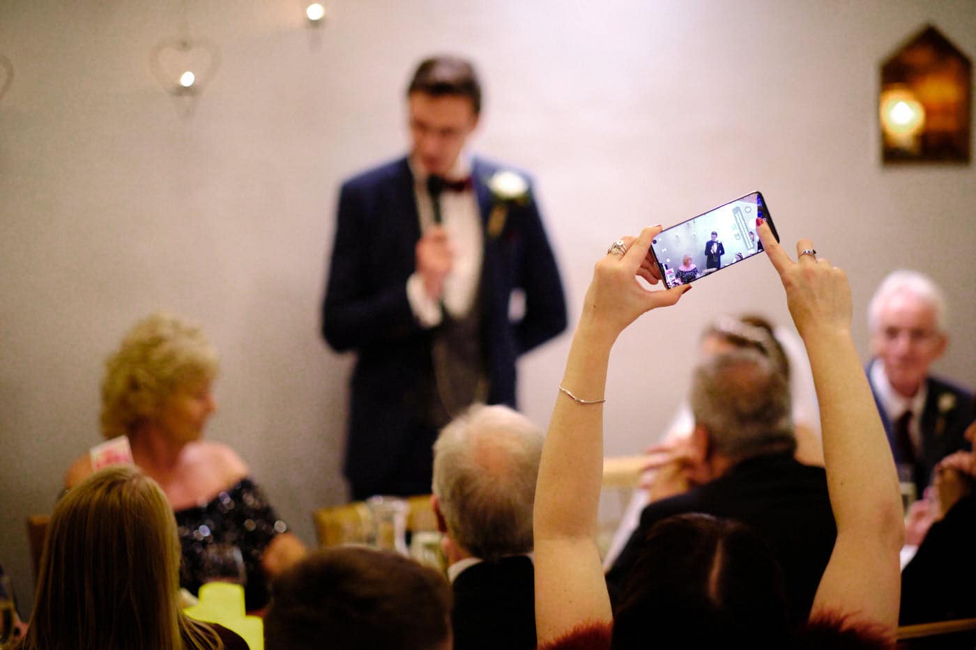 Guests taking photo of groom during speech