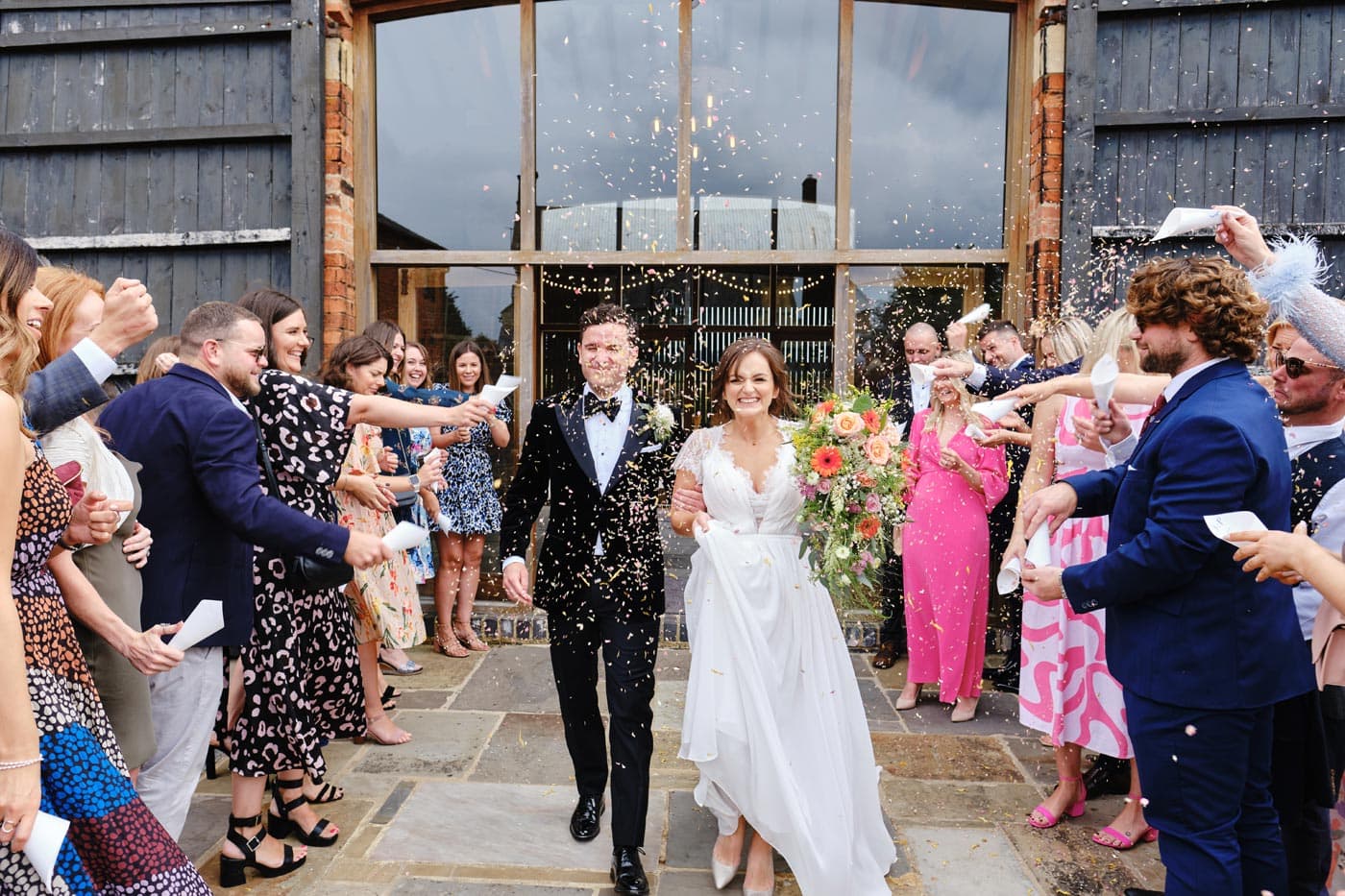 Bride and groom confetti exit as captured by their Cotswold wedding photographer
